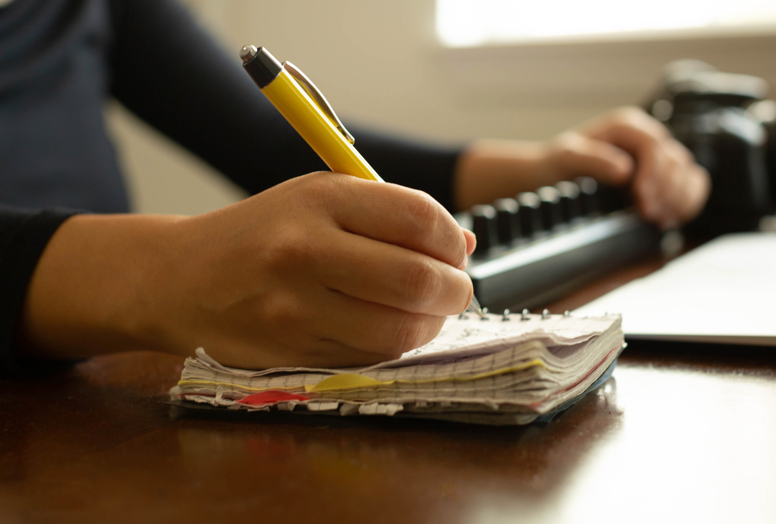 A financial reporter writing down ideas and researching with her computer