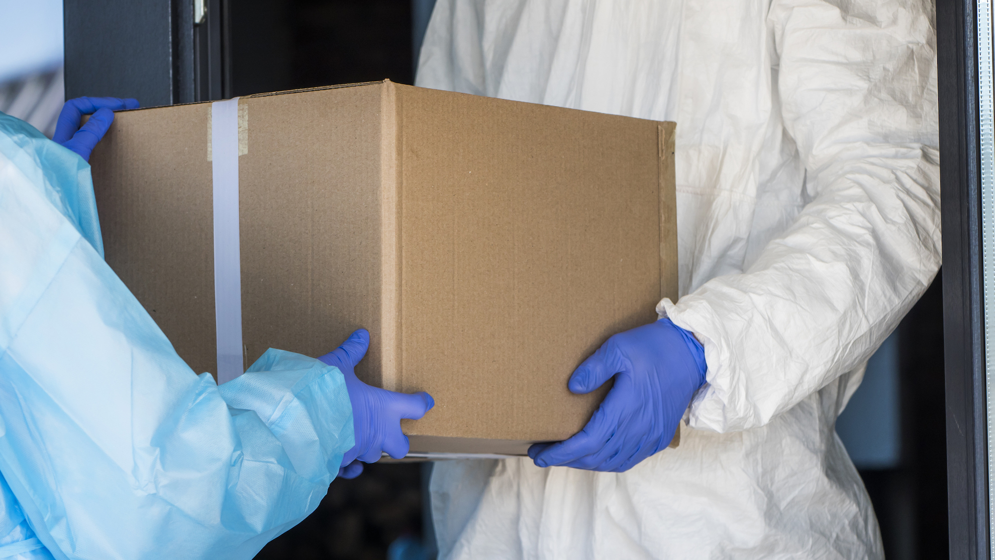 Workers in protective gear hand off a medical supply box.