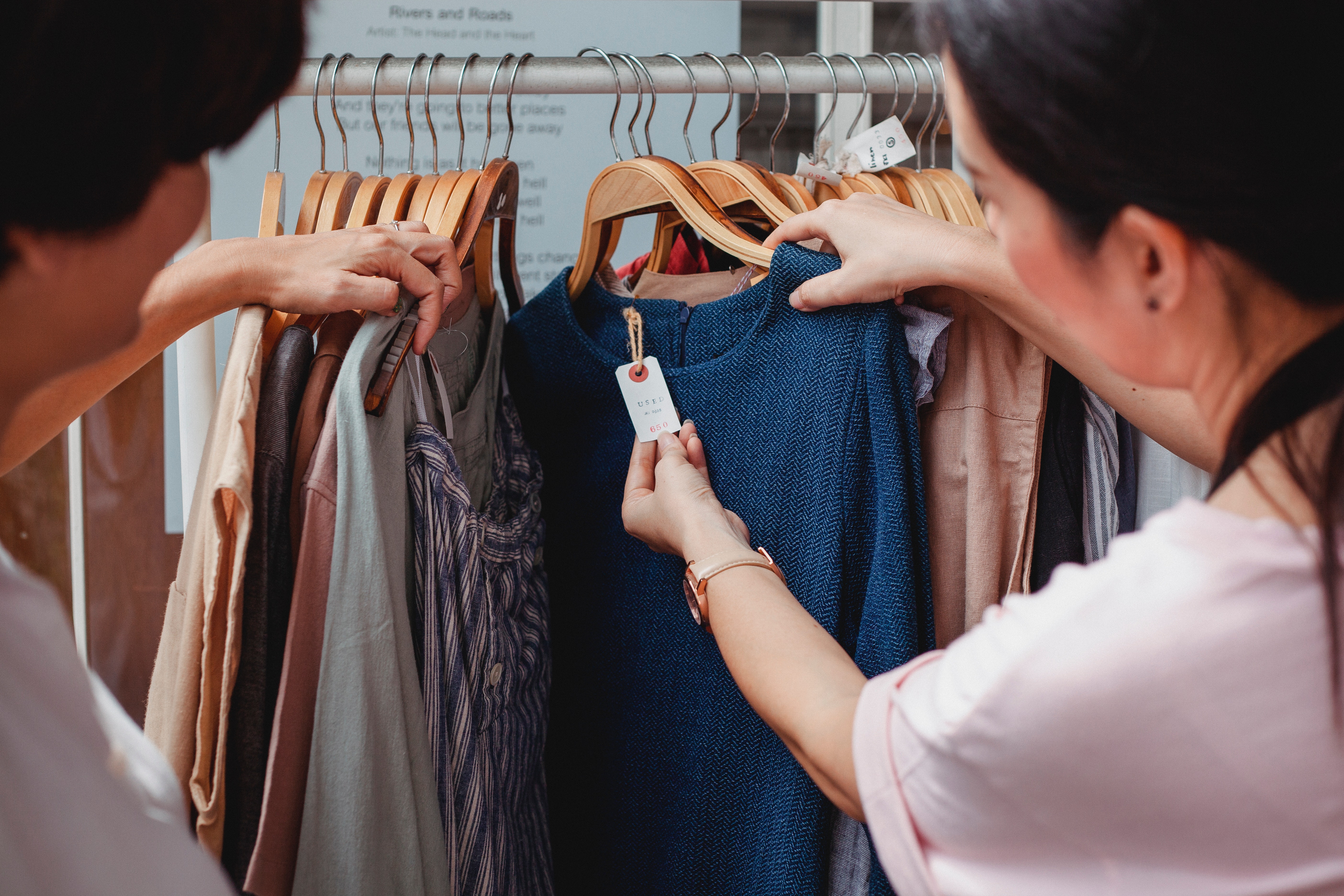 Two shoppers look at the price tag of a clothing item.