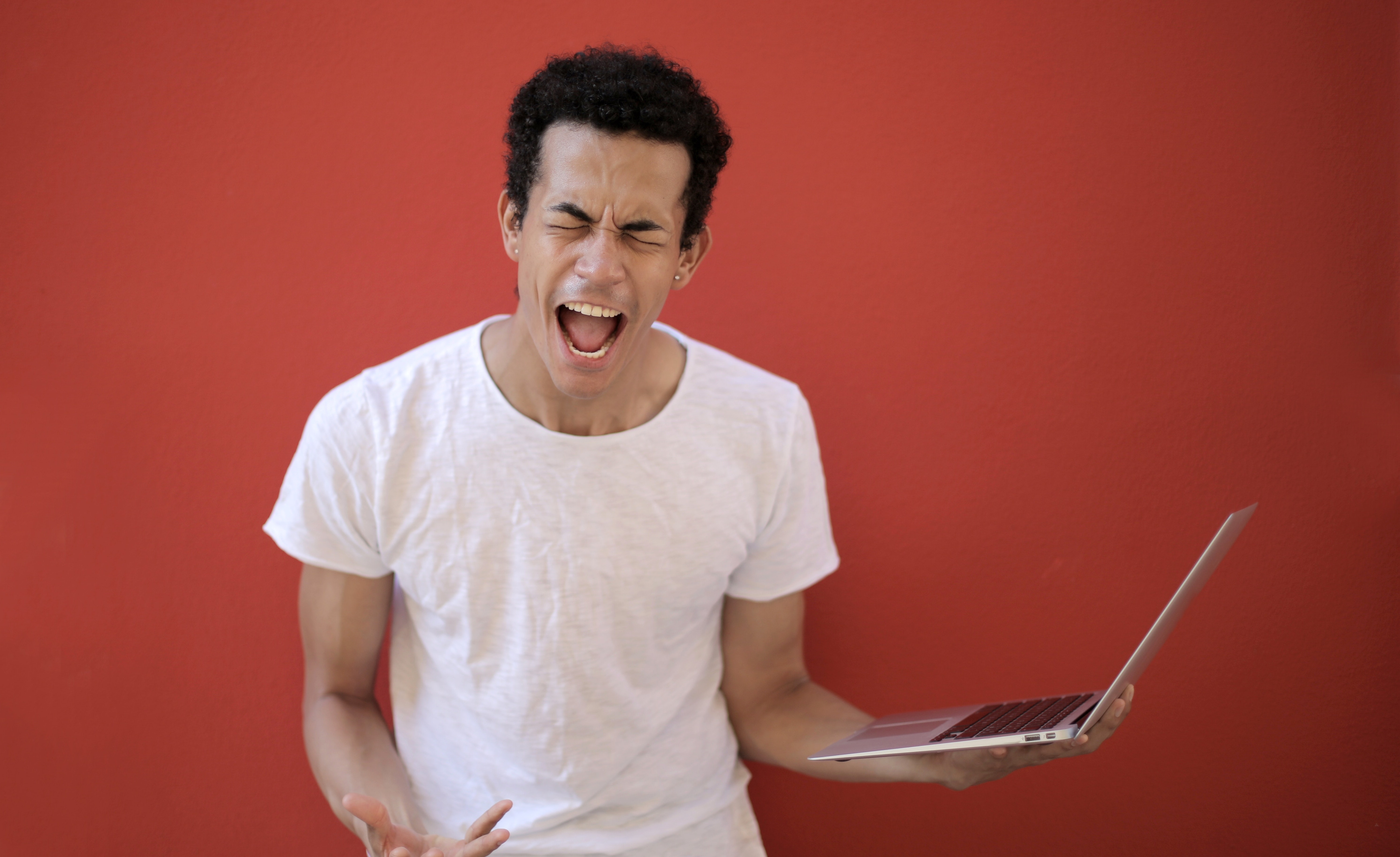 Man screaming while holding laptop