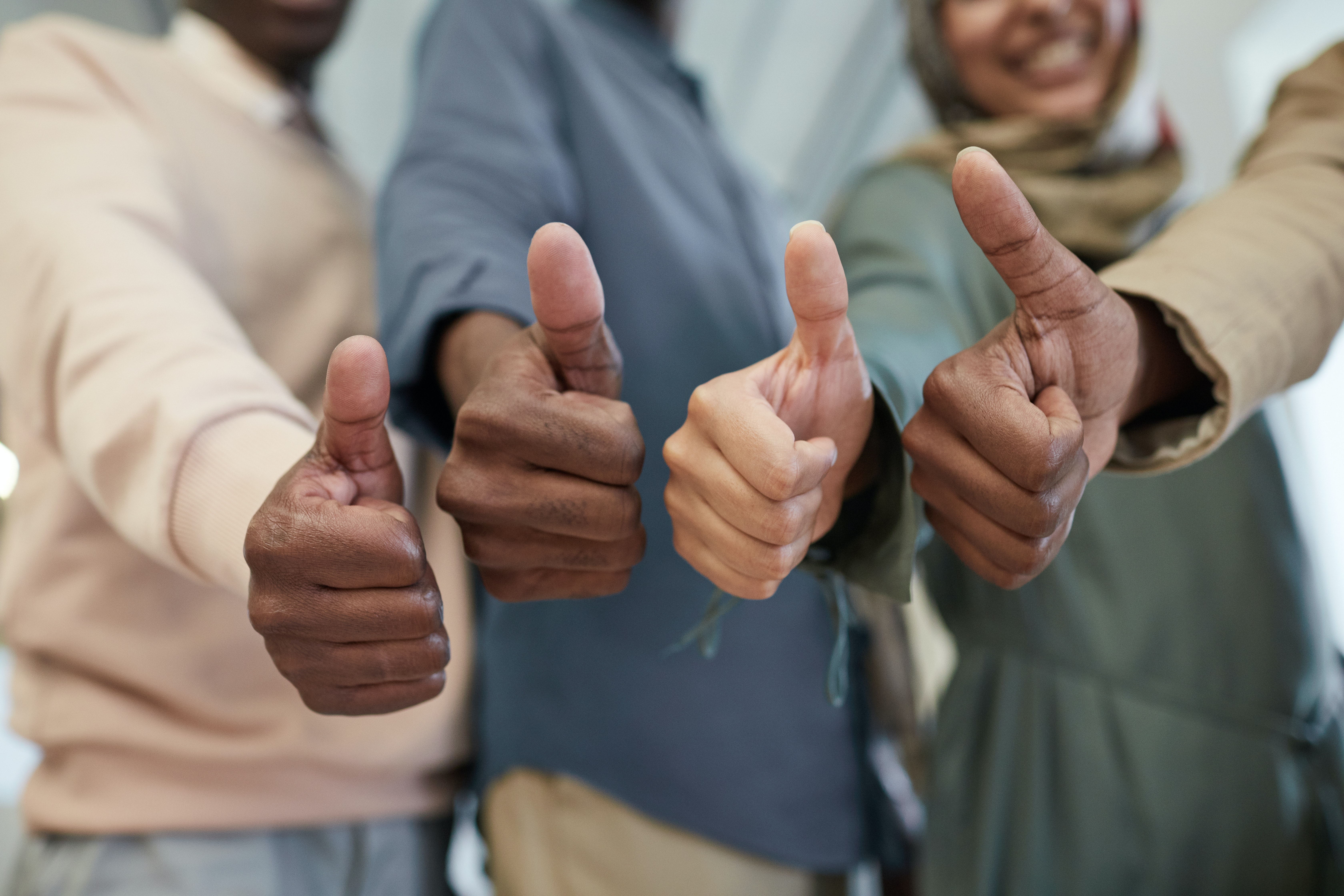 Four people give a thumbs up.