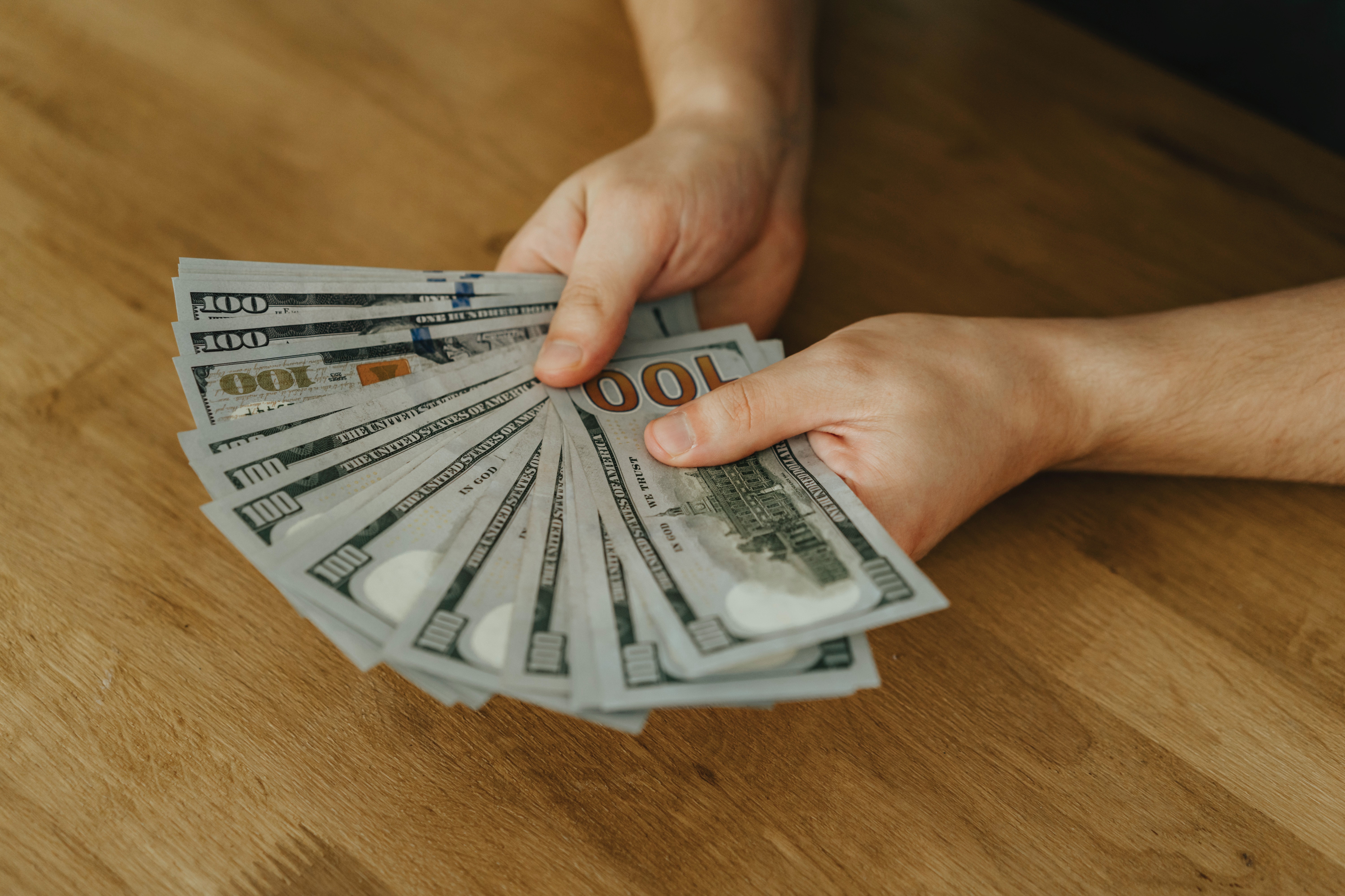 Person holding multiple $100 bills.