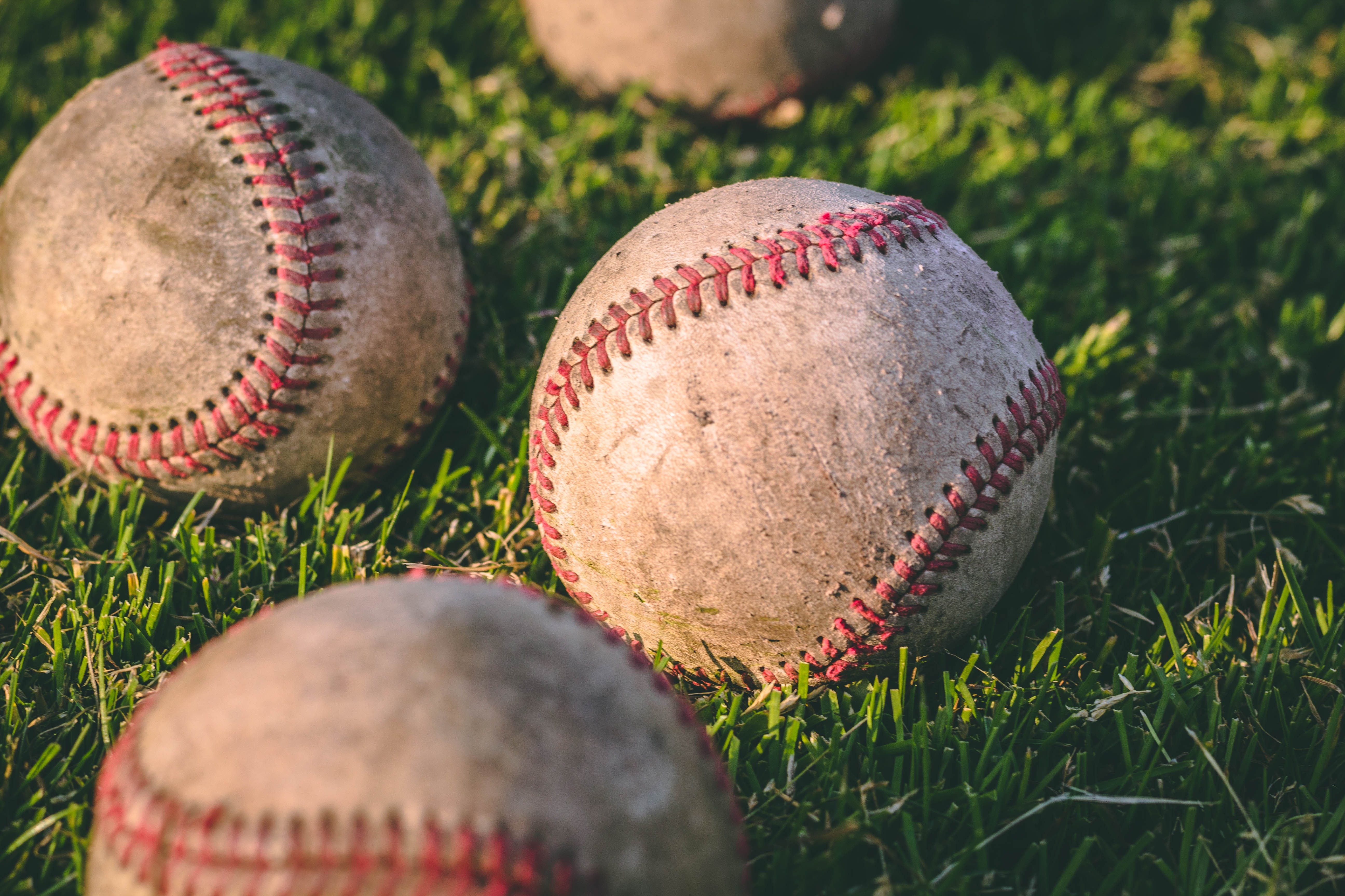 Three baseballs in a field.