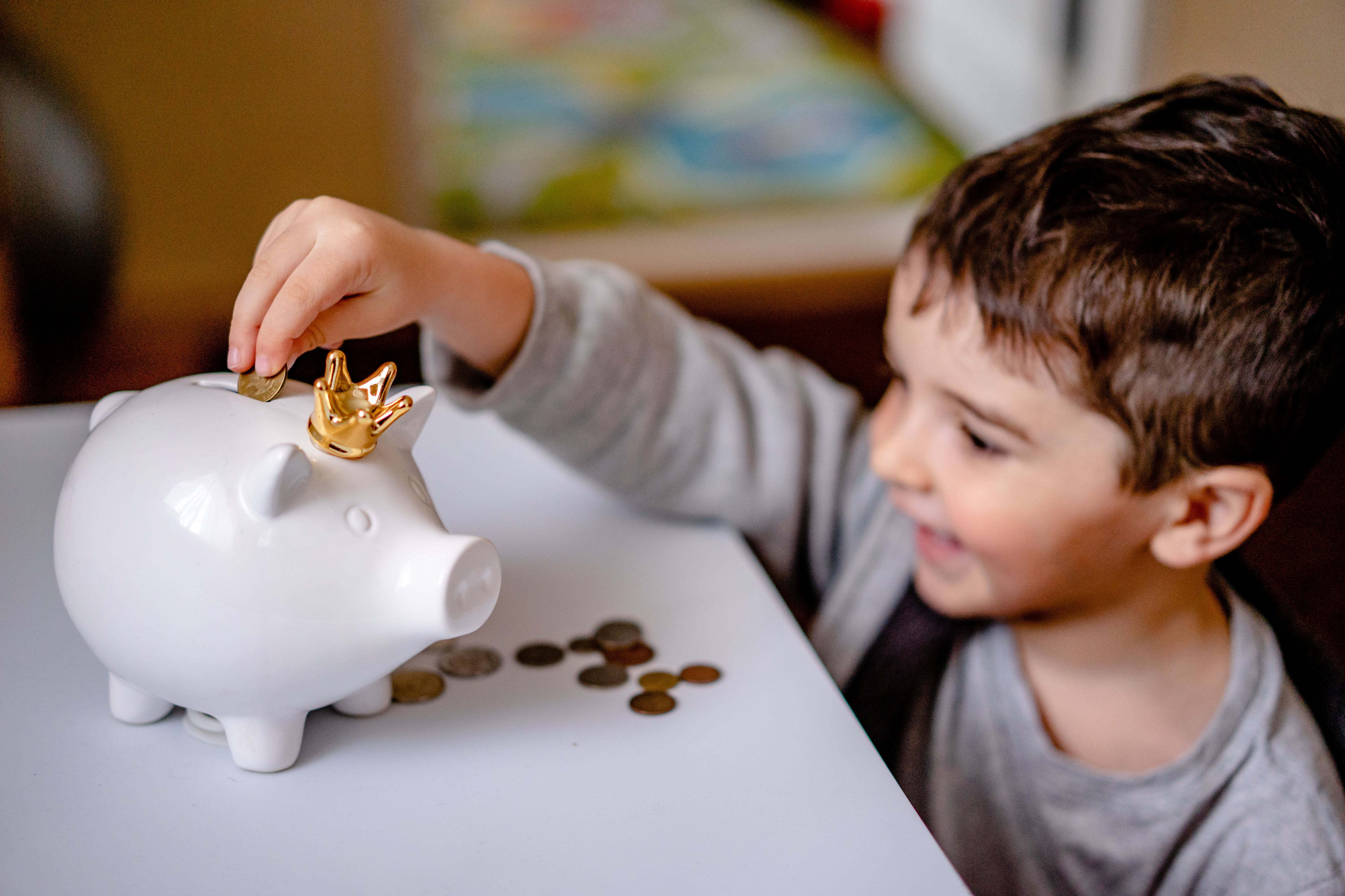 Child putting coins in a piggy bank.
