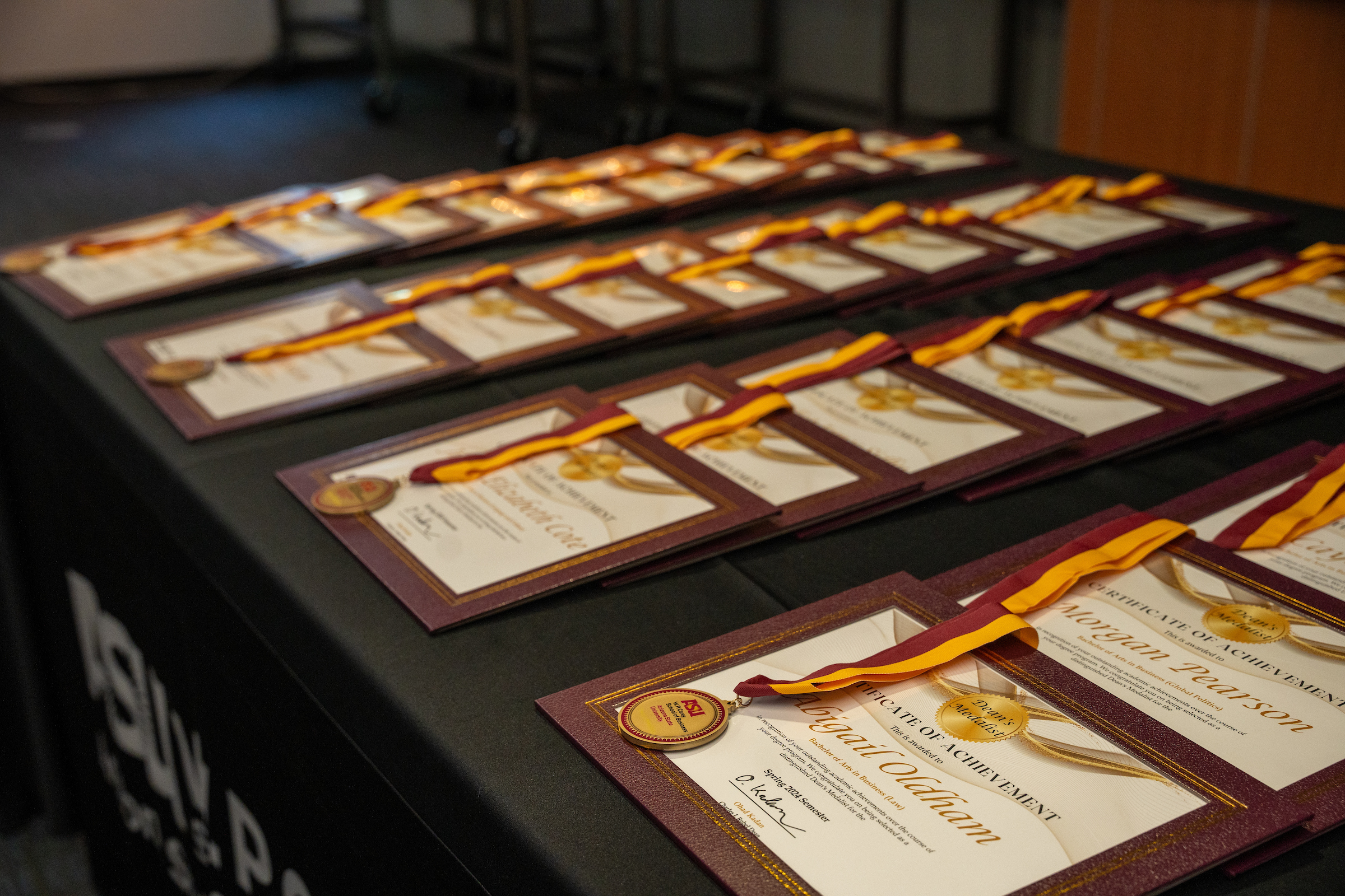 A table covered with Dean's Medalist certificates and medals.