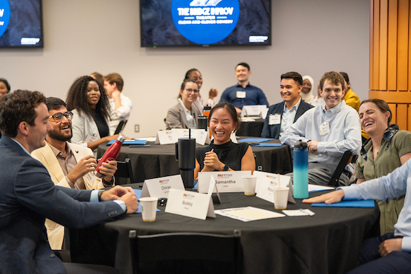 W. P. Carey MBA students smiling and talking around a table at an improv workshop during MBA orientation