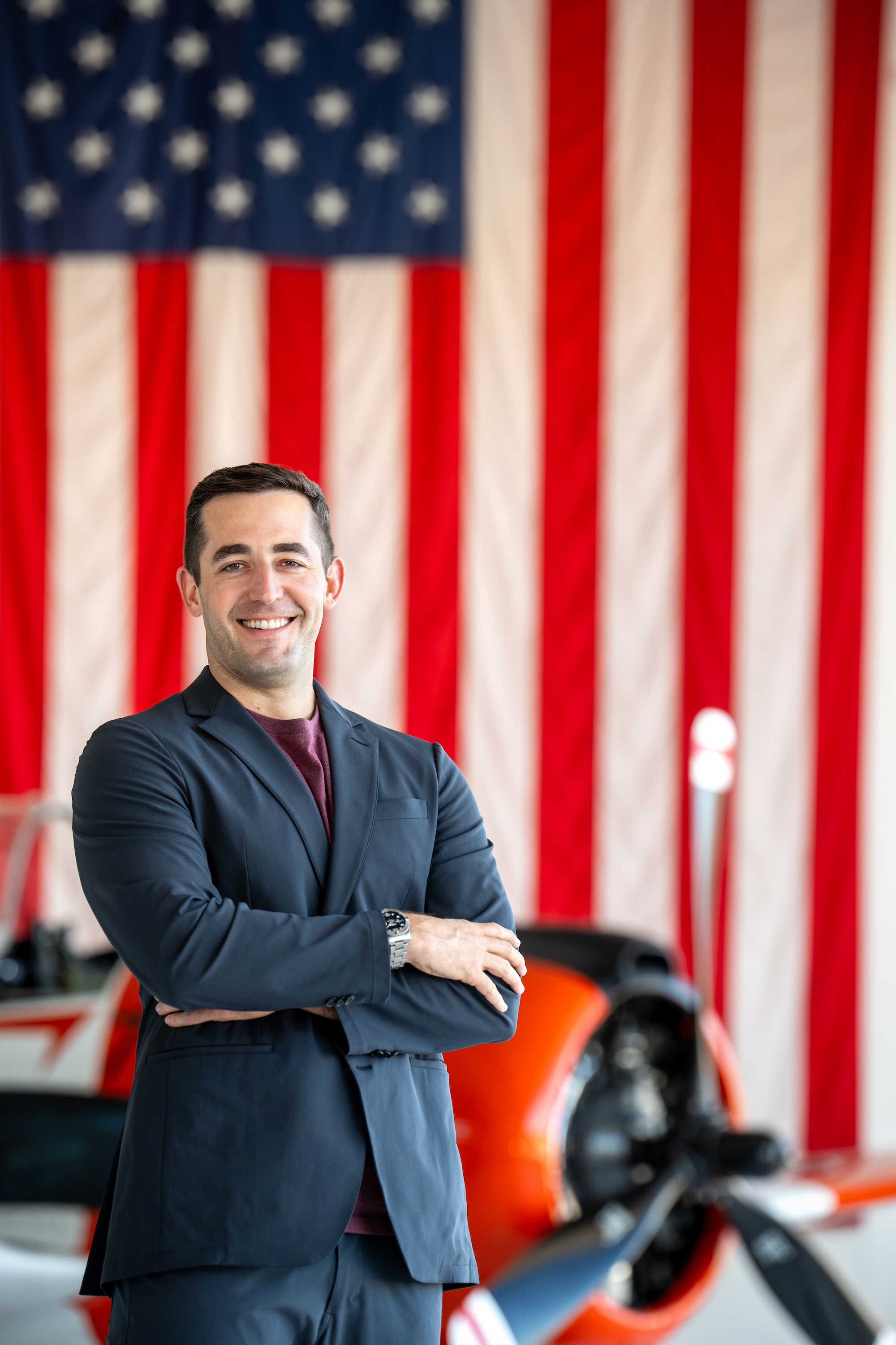 MBA alumnus Mike Shufeldt standing and smiling in front of an American flag