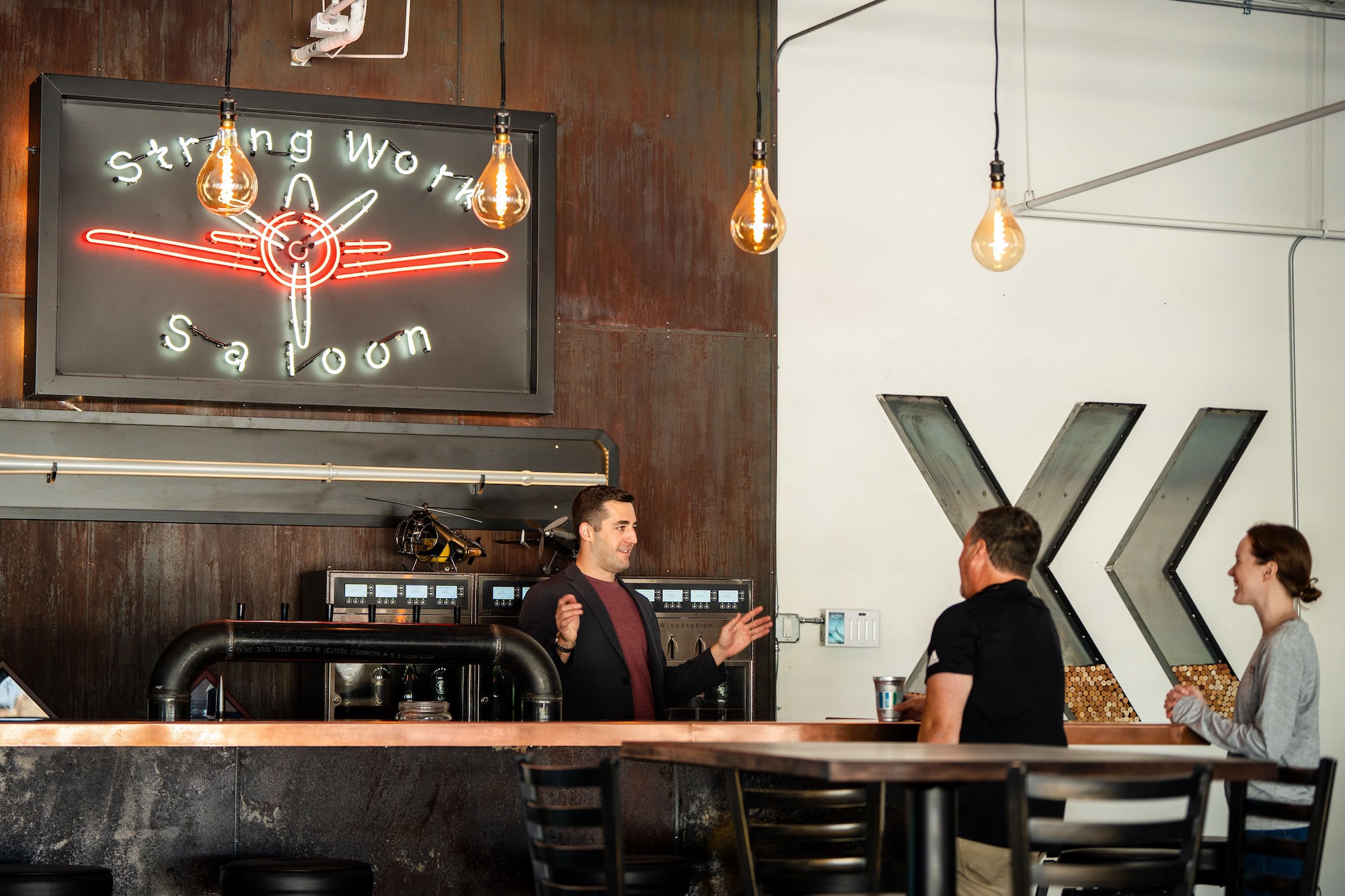 MBA alumnus Mike Shufeldt standing behind a bar, talking to two people