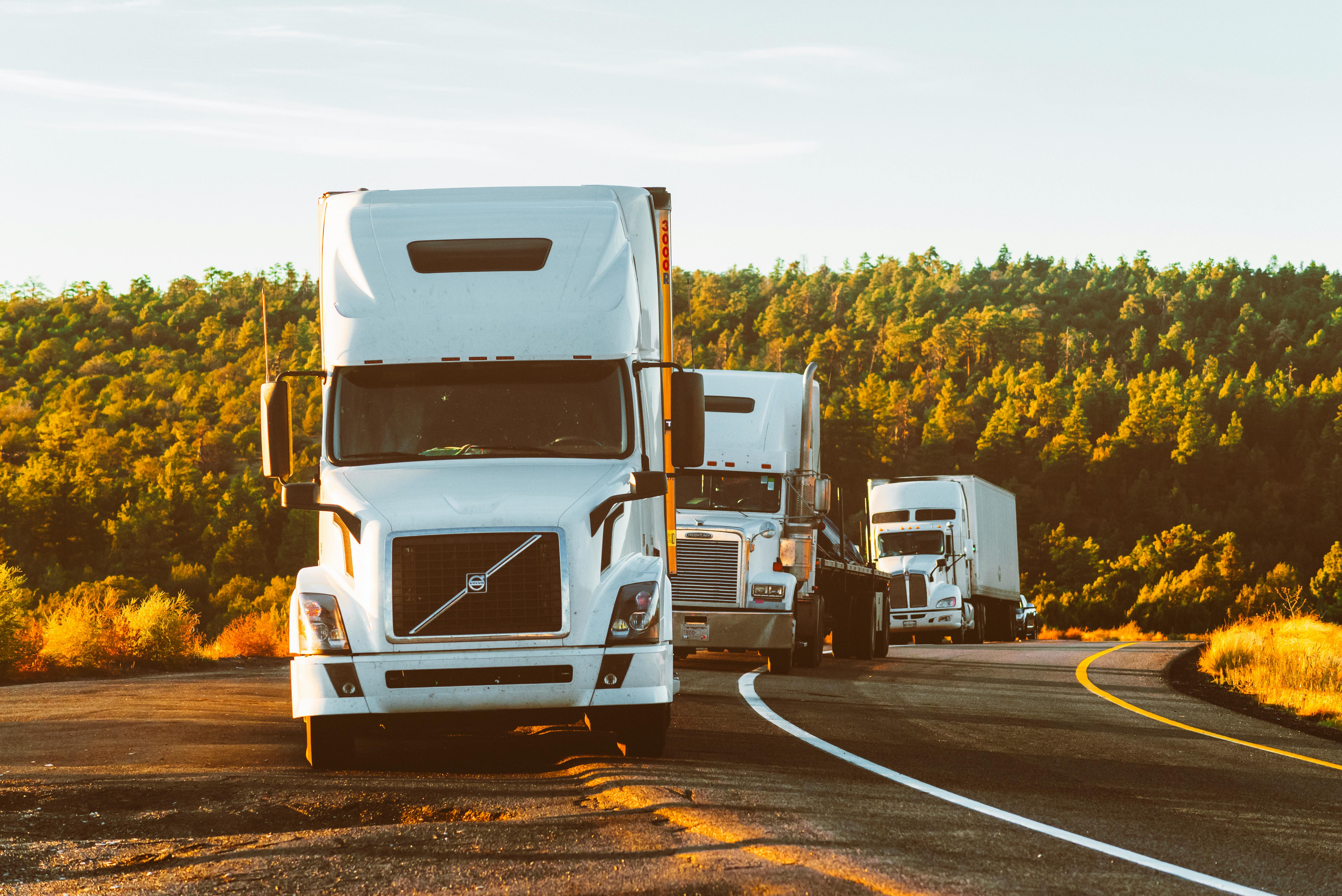 Several trucks driving down a road.