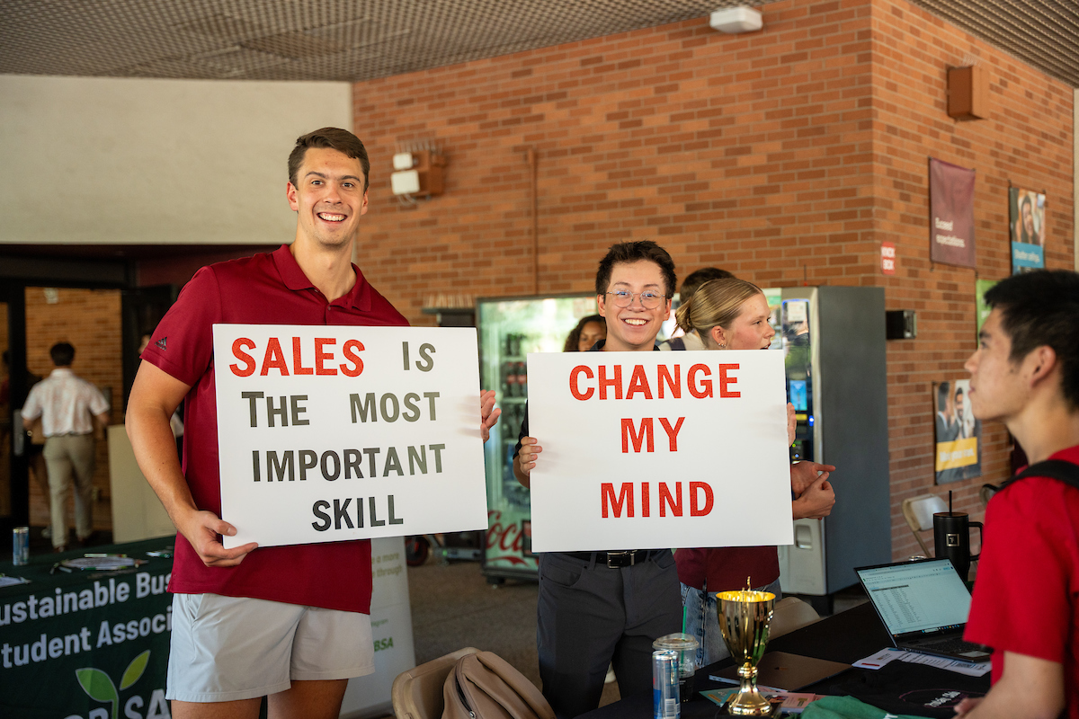 Sales club students holding a sign that says Sales is the most important skill