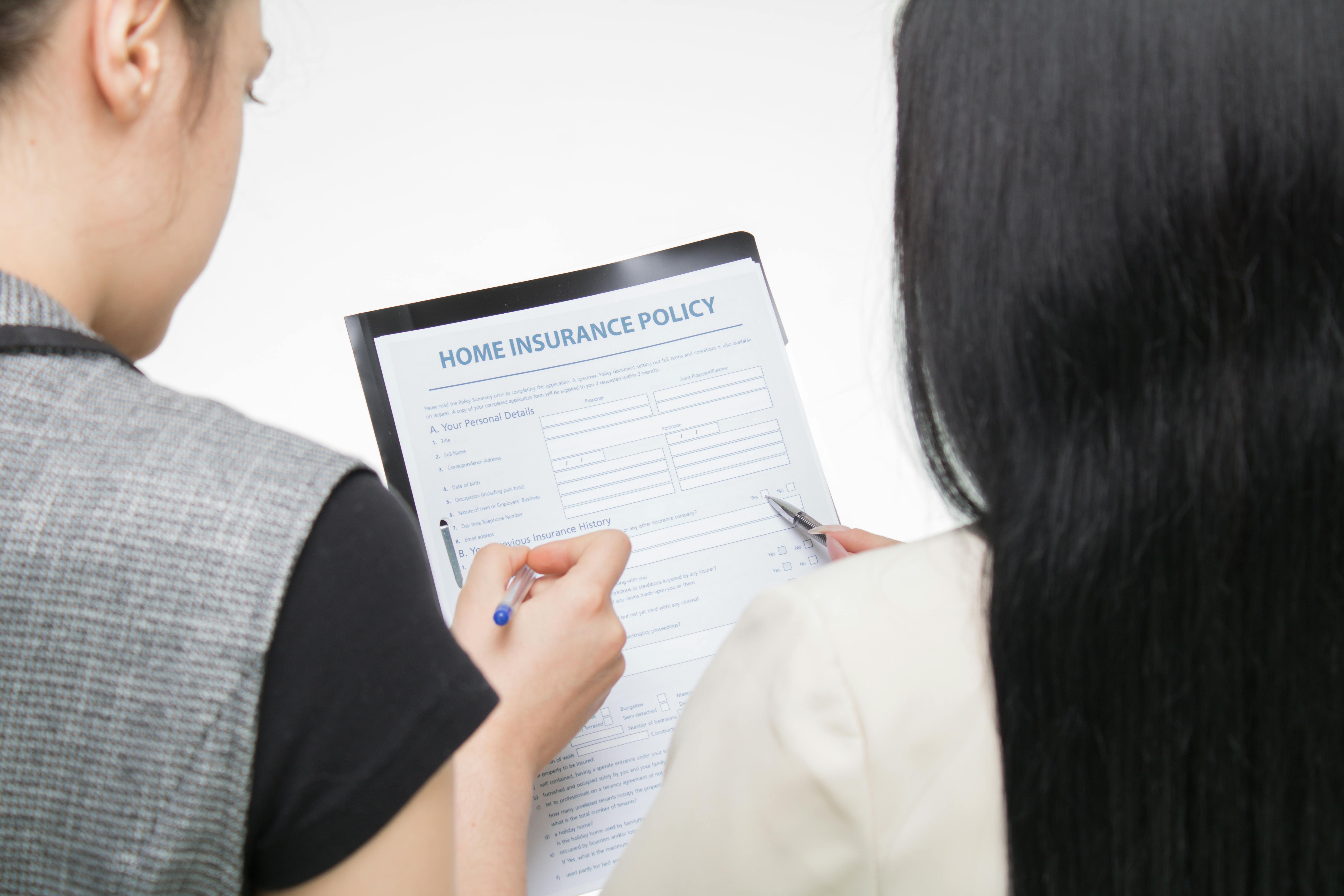 Two people signing a home insurance policy.