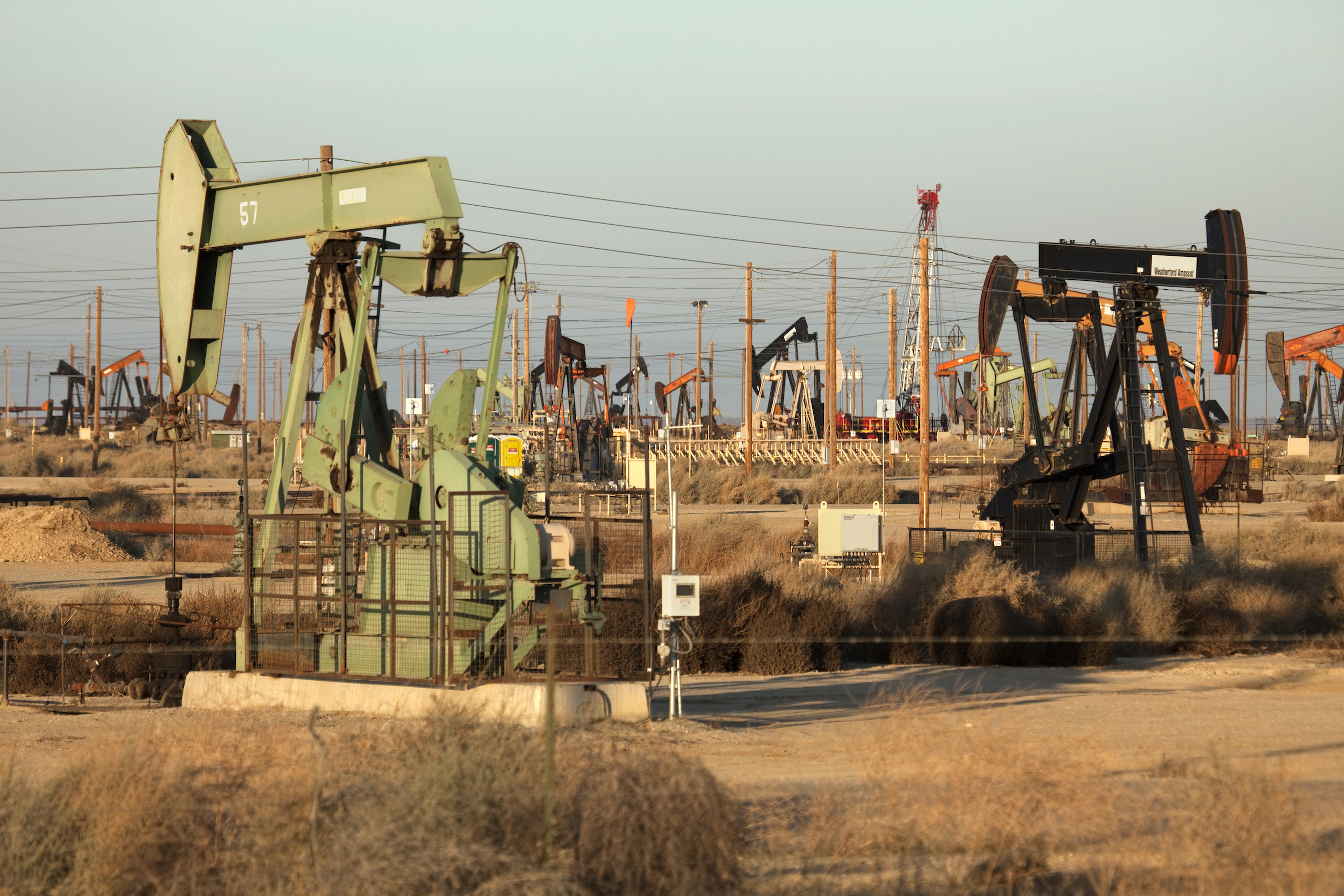 t sunset, hundreds of oil well, rigs and pumpers work off the busy Highway 46 in the oil fields of the San Joaquin Valley by the town of Lost Hills west of Bakersfield, California.