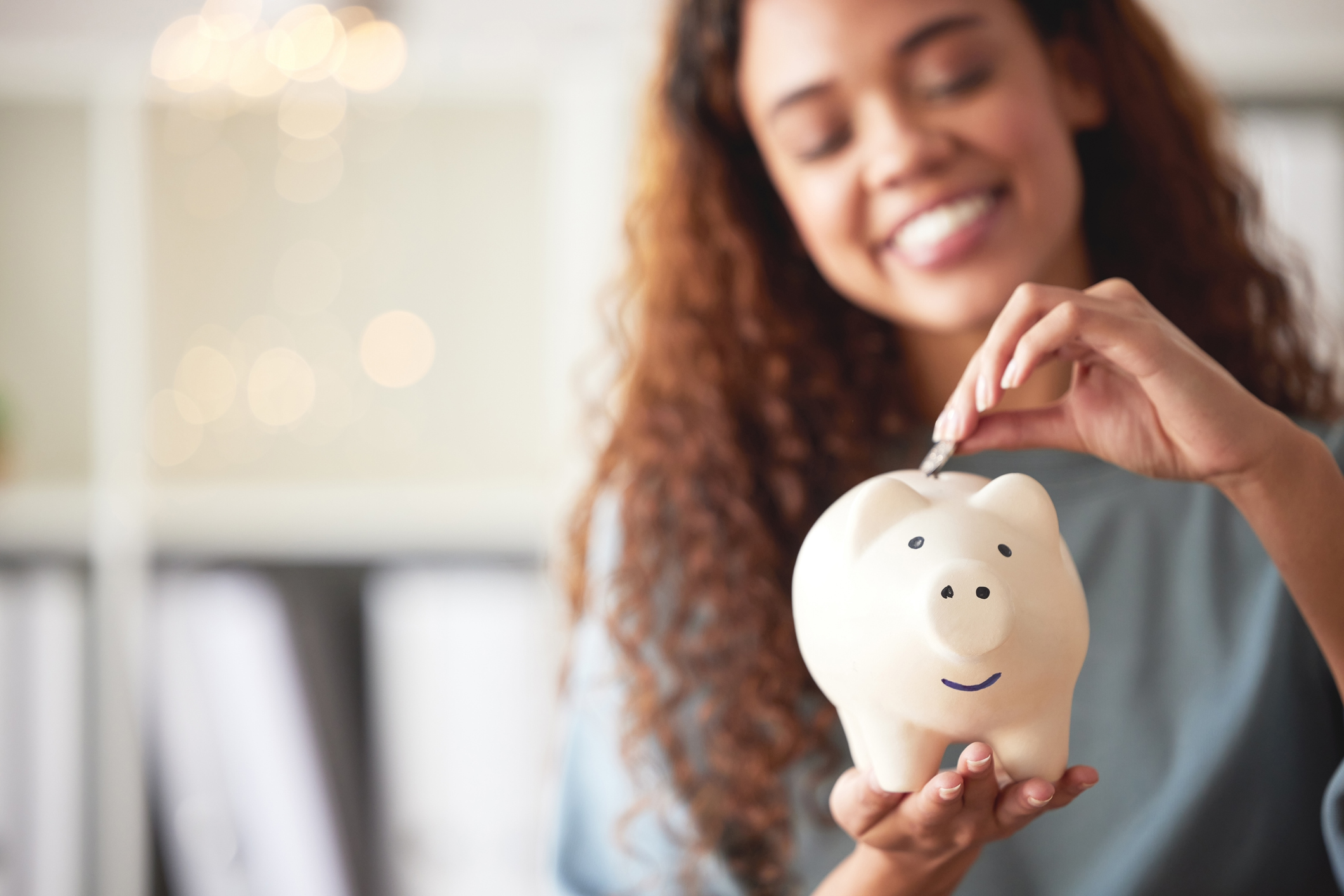 A woman puts money in a piggy bank.