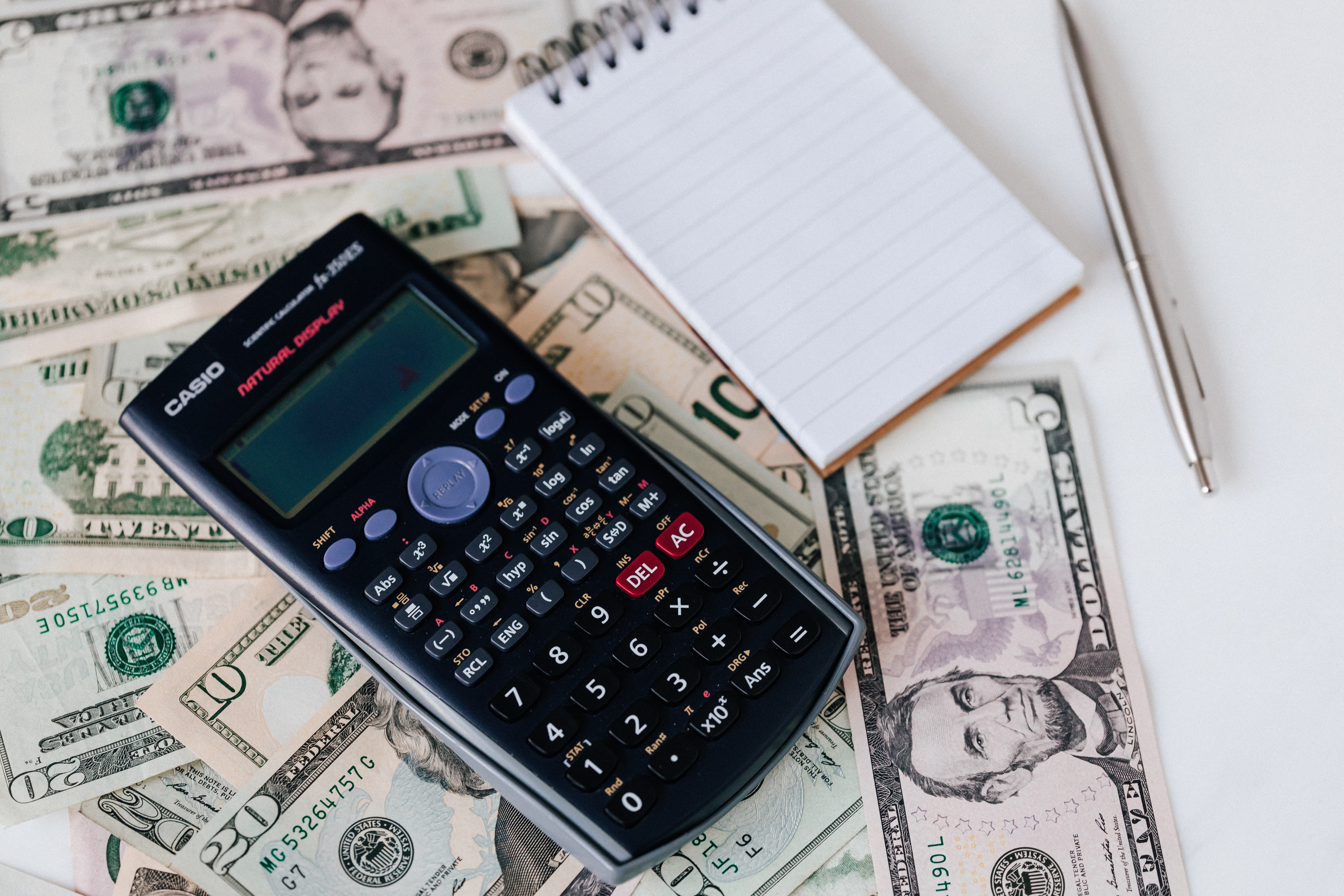 Calculator sitting on multiple paper money bills.