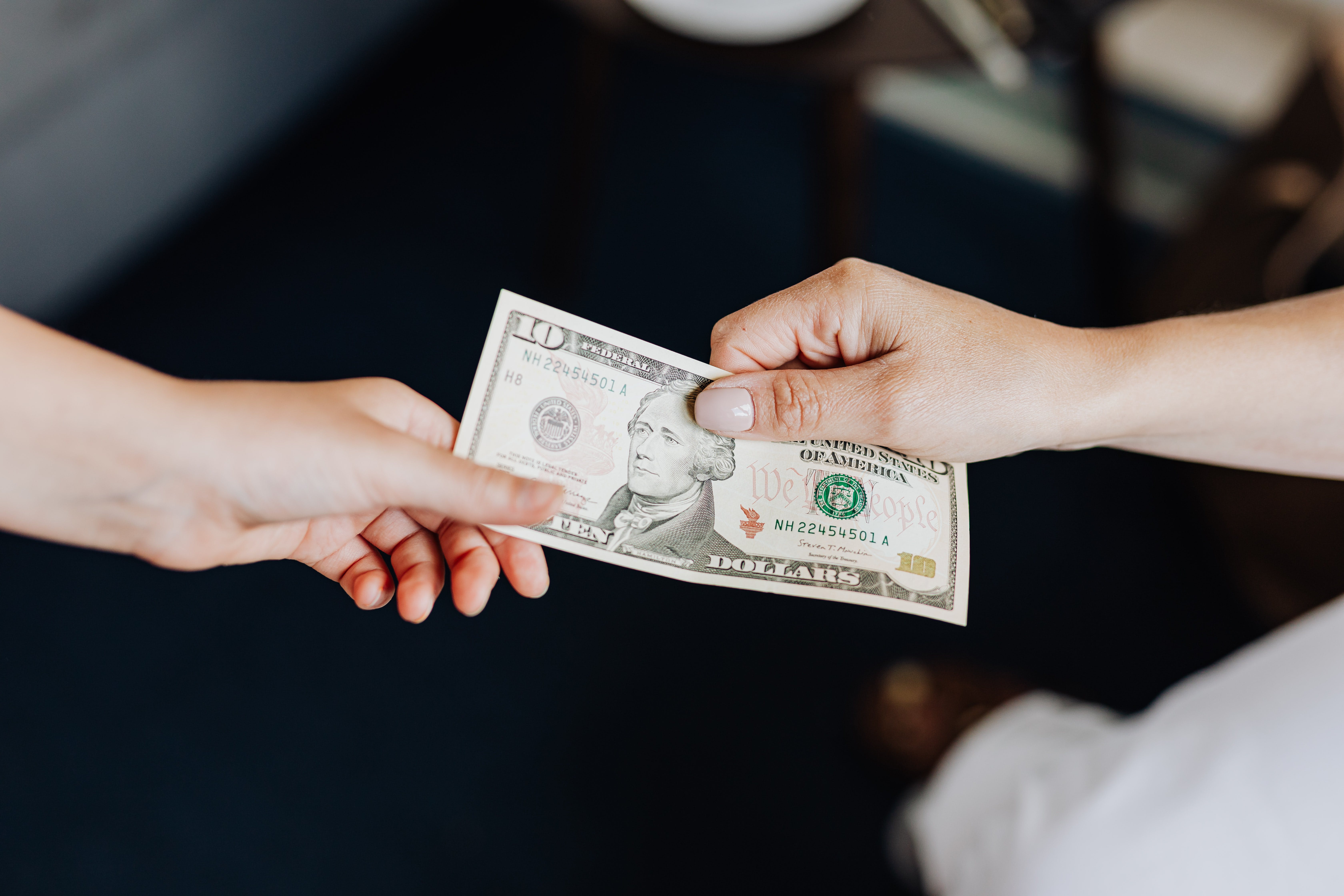 Two people holding a $10 bill.