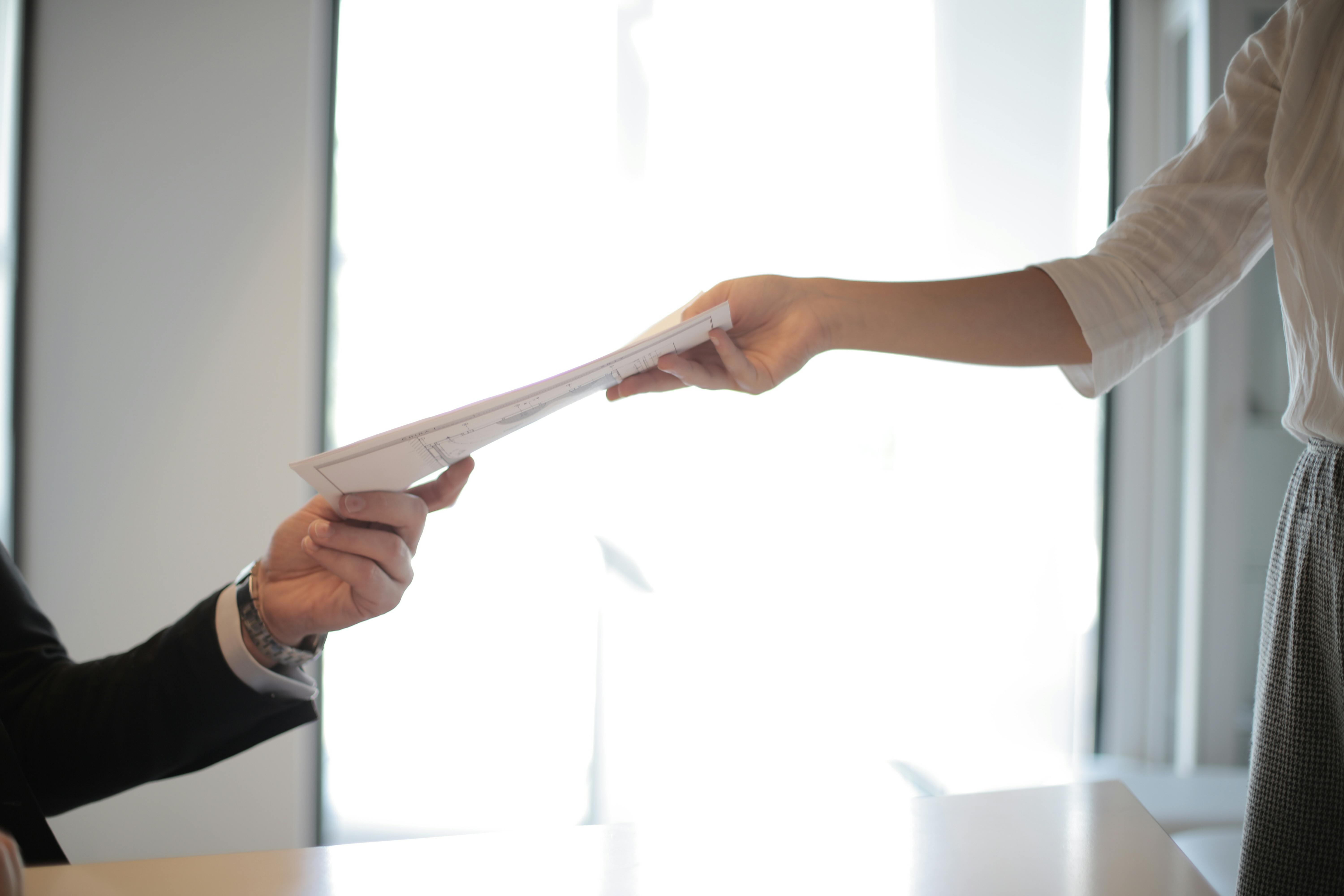 Person handing a resume to another person.