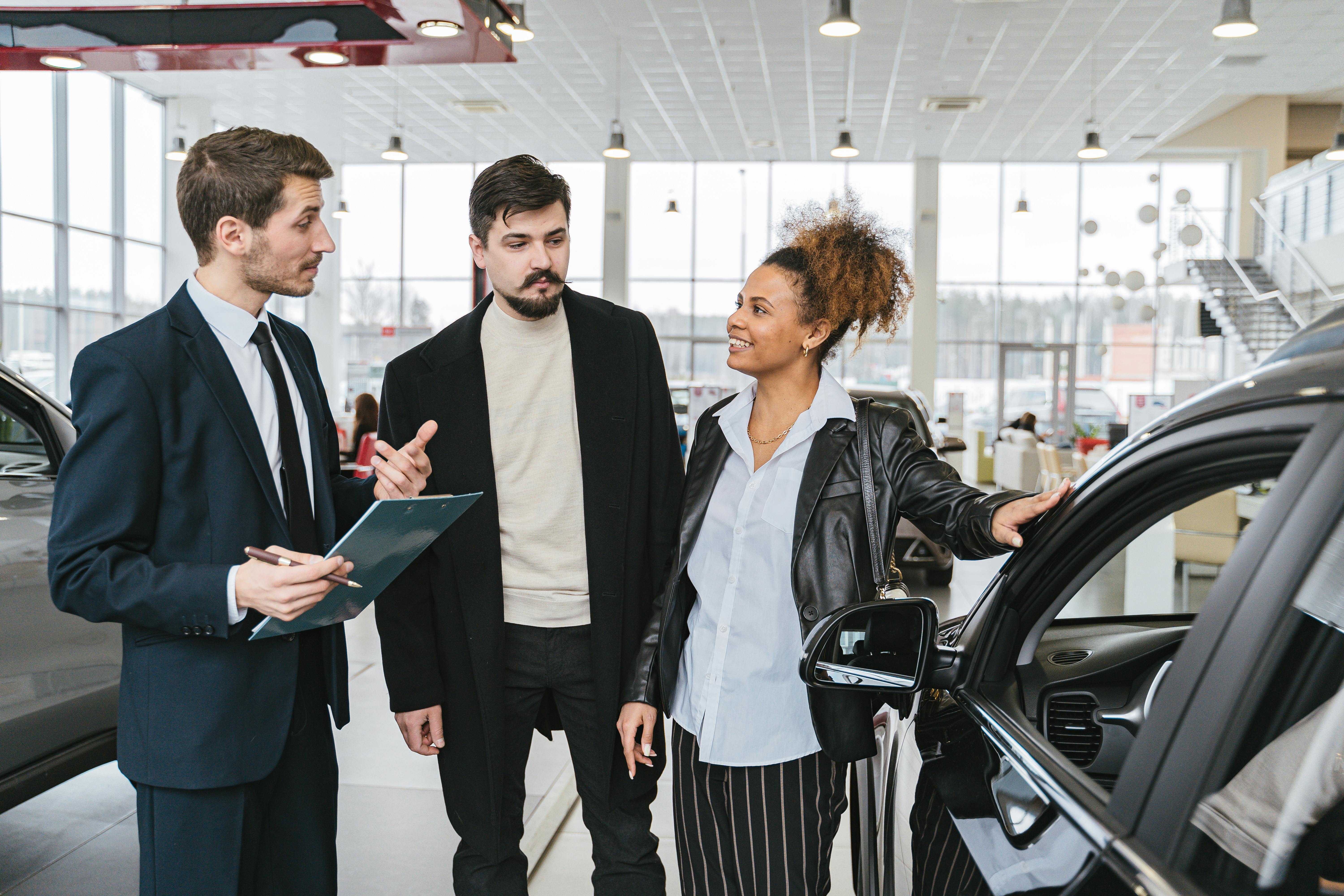 individuals talking at a car dealership