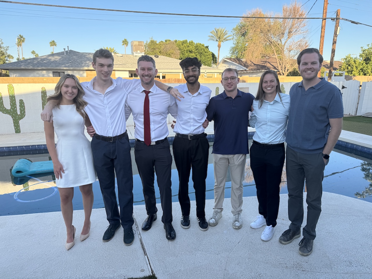 Alex Holt by a pool with some of his MS-FIN classmates